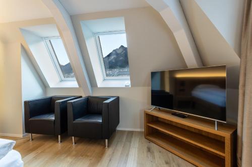 a living room with two chairs and a flat screen tv at ABC Swiss Quality Hotel in Chur
