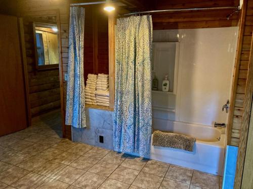 a bathroom with a tub and a shower curtain at Garden Grove Retreat & Lodging near Pictured Rocks, Fayette, Trails in Garden