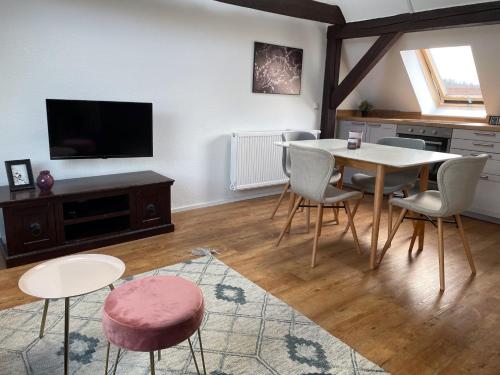 a living room with a table and chairs and a tv at discovAIR Eisenach - Dachstudio Emma - Schwimmbad-Nah mit Netflix in Eisenach