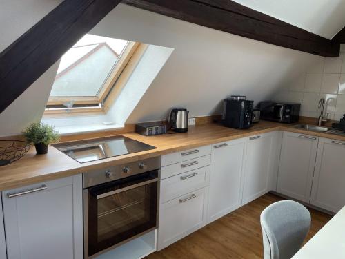 a kitchen with white cabinets and a window at discovAIR Eisenach - Dachstudio Emma - Schwimmbad-Nah mit Netflix in Eisenach