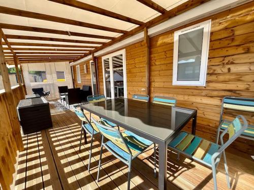 - une table à manger et des chaises dans une pièce dotée d'un mur en bois dans l'établissement Bungalow neuf avec belle terrasse couverte et piscine, à Corcieux