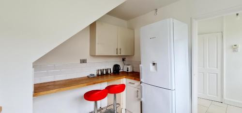 a kitchen with white cabinets and red stools at Grace Double Bedroom Manchester in Middleton
