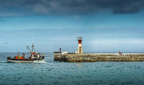 a small boat in the water near a lighthouse at Charming Coastal Townhouse at The Majestic in Kalk Bay
