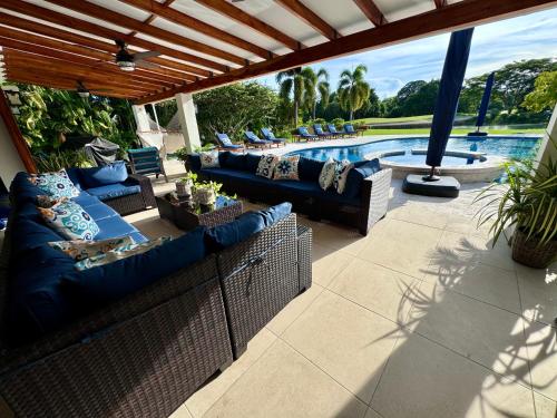 a patio with blue couches and a swimming pool at Villa Solara 6 - Luxury 6 Bedroom Villa with Pool, Golf & Lake View in Río Hato