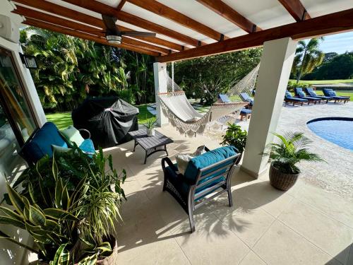 a patio with chairs and a hammock and a pool at Villa Solara 6 - Luxury 6 Bedroom Villa with Pool, Golf & Lake View in Río Hato