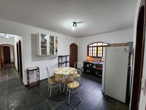 a kitchen with a table and a refrigerator at Casa Peruibe frente a praia in Peruíbe