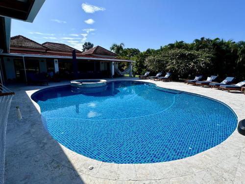 a large blue swimming pool with chairs around it at Villa Solara 6 - Luxury 6 Bedroom Villa with Pool, Golf & Lake View in Río Hato