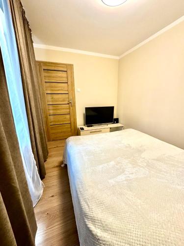 a small bedroom with a bed and a television at Piekary C in Legnica