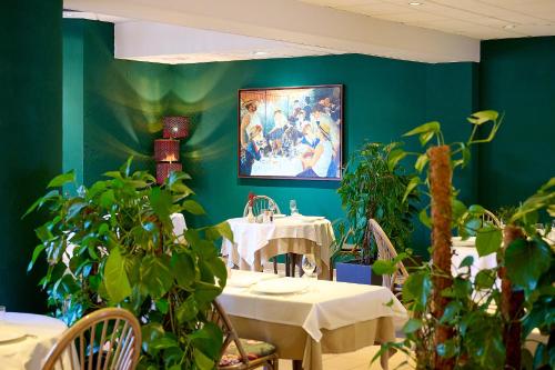 a dining room with tables and potted plants at Logis L'Ermitage Hôtel & Restaurant in Saulges