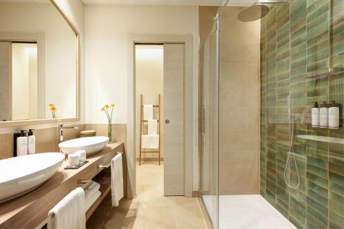 a bathroom with two sinks and a glass shower at Almar Timi Ama Resort & Spa in Villasimius