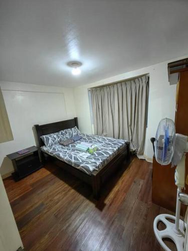 a bedroom with a bed in a room with wooden floors at Cozy Townhouse own parking Wi-Fi in Baguio