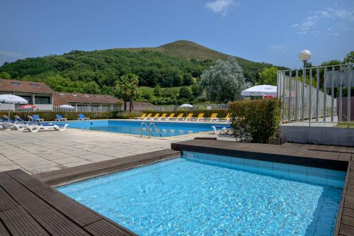 une grande piscine avec des chaises et une montagne dans l'établissement Village Club Le Saint Ignace, à Ascain
