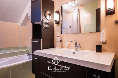 une salle de bain avec un lavabo, une baignoire et un miroir dans l'établissement Maison familiale à Spay avec piscine, jeux & piano, à Spay