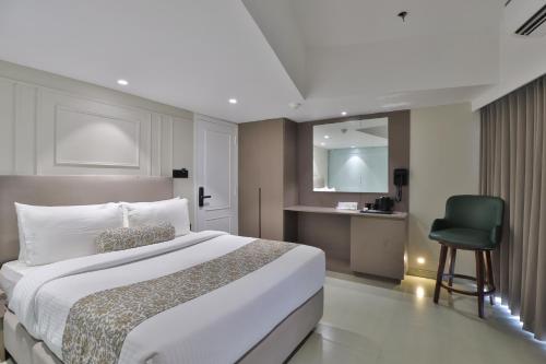 a bedroom with a large bed and a green chair at Hotel The Grand Suites in Ahmedabad