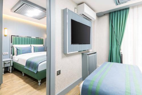 a hotel room with a bed and a flat screen tv at Santa Rio Gold Taxim Hotel in Istanbul