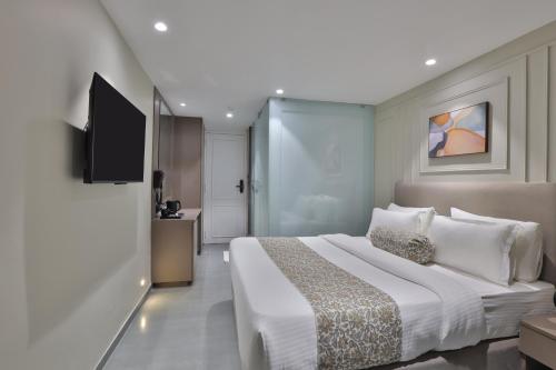 a hotel room with a large bed and a television at Hotel The Grand Suites in Ahmedabad