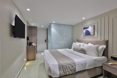 a bedroom with a large white bed and a television at Hotel The Grand Suites in Ahmedabad
