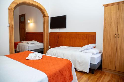 a hotel room with two beds and a flat screen tv at Hotel Plaza in Punta Arenas