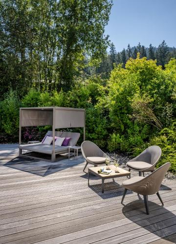 a deck with chairs and a bed and a table at Hotel Der Bär in Ellmau