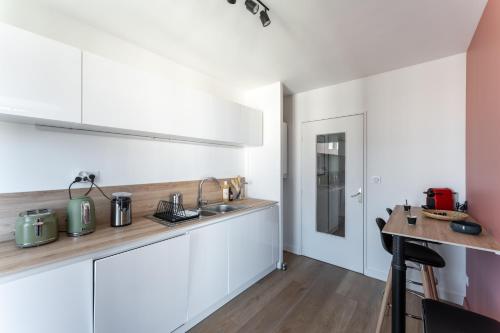 une cuisine avec des armoires blanches et un comptoir dans l'établissement MDOR - Montagari Appt à Lyon, à Lyon