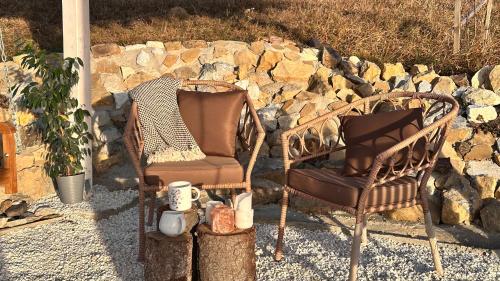 two chairs sitting in front of a stone wall at Dorna Iglu Luxury Glamping Resort in Dorna Cîndrenilor