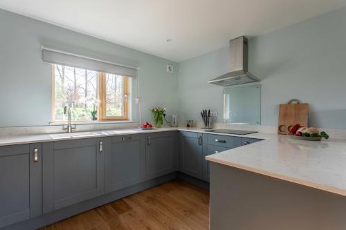 a kitchen with blue cabinets and a window at 1 Beechwood at Thoulstone Park in Westbury