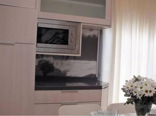 a kitchen with a microwave and a vase of flowers at Beach Bungalows - Casal dos Patos - Vila Norte in Lourinhã