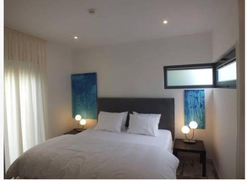 a bedroom with a large white bed with two lamps at Beach Bungalows - Casal dos Patos - Vila Norte in Lourinhã