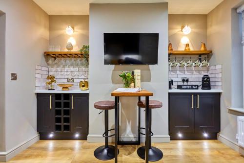 a bar with stools and a tv in a room at Fig Tree House in Great Malvern