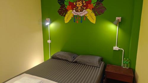 a bedroom with a green wall with a bed at The Funky Monkey Hostel - 18 to 40 years old only in Haad Rin