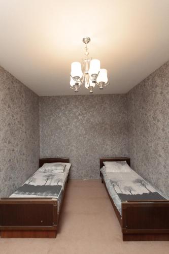 a bedroom with two beds and a chandelier at Cozy Home Gabala in Gabala