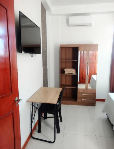 a room with a wooden table and a bedroom at Deluxe Hotel Talara in Talara