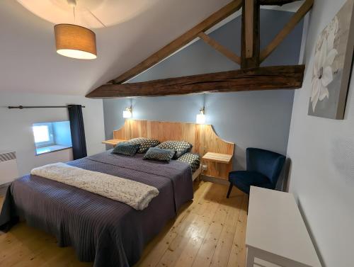a bedroom with a bed and a blue chair at La Bonne Chauffe - Serpentin in Verrières