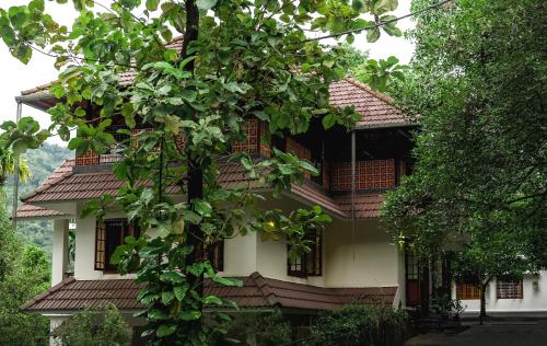 a building with a tree in front of it at Jathikka Homestay in Vagamon