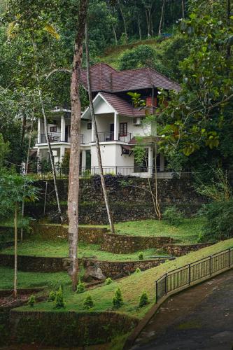 a white house on top of a hill at Jathikka Homestay in Vagamon