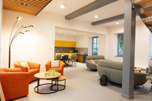 un salon avec des chaises orange et une table dans l'établissement Uch-y-Gite BY PRIMO CONClERGERIE, à Uchizy