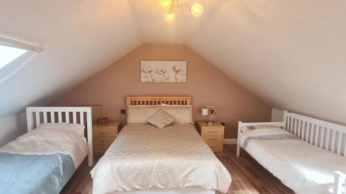 a attic bedroom with two beds and a chandelier at Hartcliffe Retreat in Penistone