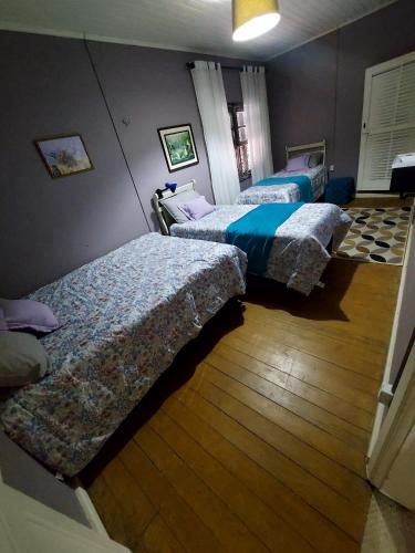 three beds in a room with wooden floors at Hotel Dom Paulo in Lapa