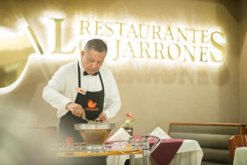 a man in a kitchen preparing food on a table at HOTEL DON MIGUEl in Tapachula