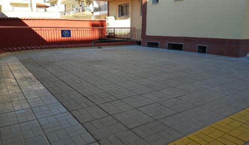 a large courtyard with a brick building and a white wall at Stella Family Apartments in Síndos