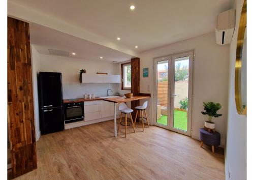 Il comprend une cuisine équipée d'un réfrigérateur noir et d'une table. dans l'établissement Appartement de charme proche de la mer, à Palavas-les-Flots