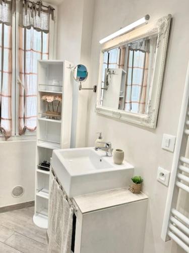 une salle de bain blanche avec un lavabo et un miroir dans l'établissement Le Palmero Centre ville, plage, clim, à Menton