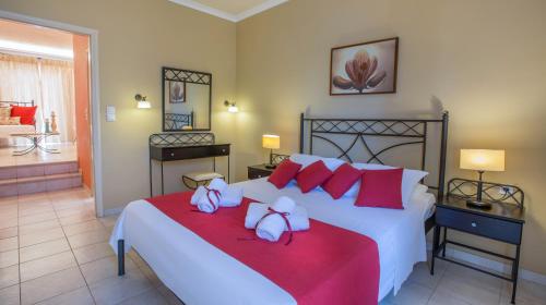 a bedroom with a large white bed with red pillows at Oasis Beach Hotel in Skala