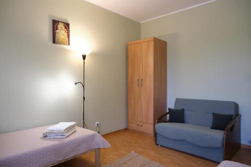 a room with a chair and a table and a lamp at Jono Pauliaus II piligrimu namai in Raseiniai