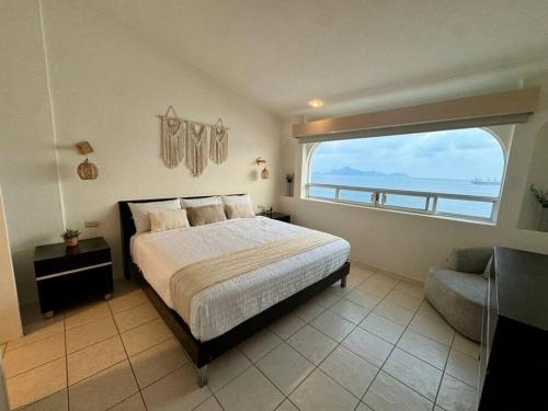a bedroom with a bed and a large window at Vista al Mar, Terraza y Albercas in Manzanillo