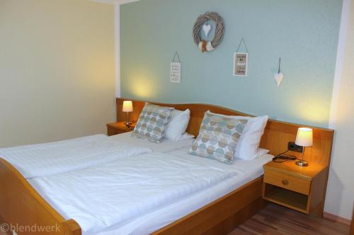 Schlafzimmer mit einem Bett mit weißer Bettwäsche und Kissen in der Unterkunft Pension Weigert in Bodenmais