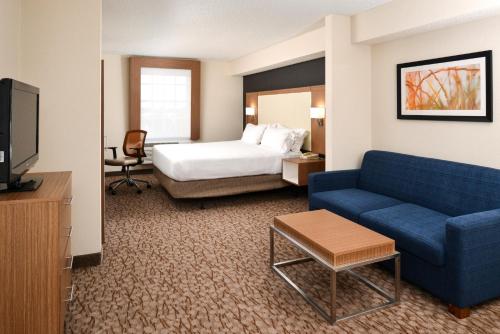una camera d'albergo con un letto e un divano blu di Holiday Inn Express Hotel & Suites Bonita Springs/Naples, an IHG Hotel a Bonita Springs