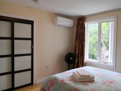 a bedroom with a bed and a window with towels on it at Dairy Homestay in Toronto