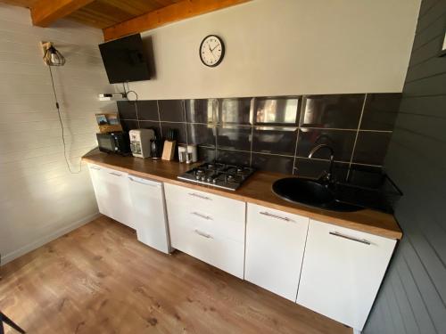 a kitchen with a sink and a clock on the wall at Domki że Hej Bieszczady in Ustrzyki Dolne