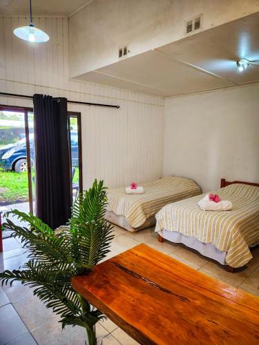 two beds in a room with a table at Tumu Cabin Rapa Nui in Hanga Roa